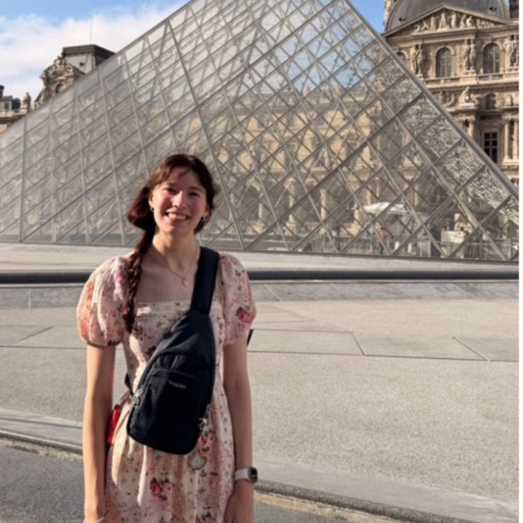 Olivia Scholin standing in front of the Louvre Pyramid in Paris